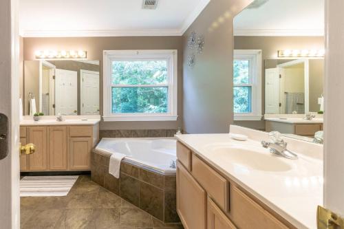 baño con bañera, 2 lavabos y ventana en Memories by the Lake, en Gainesville