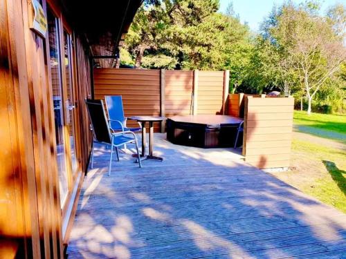 un patio con mesa y sillas junto a una casa en Oak Lodge 7 Hot Tub, en York