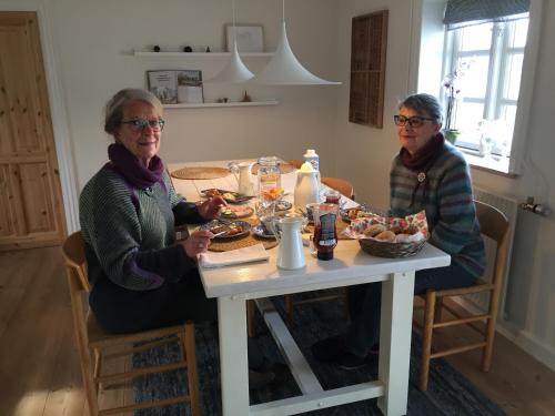 dos mujeres sentadas en una mesa comiendo comida en Aasesminde en Fåborg