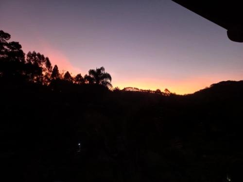a sunset over a hill with trees in the background at Pousada Solar Azul in Miguel Pereira