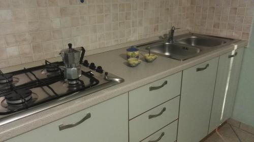 a kitchen counter with a sink and a stove at B&B IL PALOMBARO in Uggiano la Chiesa