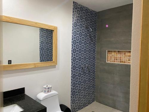 een badkamer met een douche, een spiegel en een toilet bij Kavali in Los Ayala
