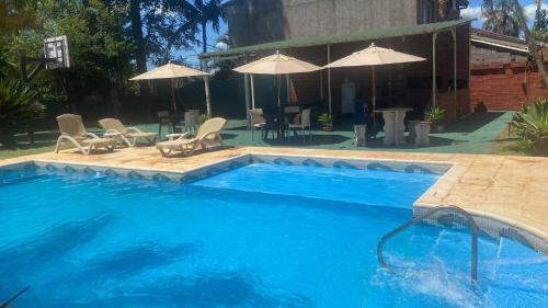 uma grande piscina azul com cadeiras e guarda-sóis em Iguassu Flower Garden em Puerto Iguazú