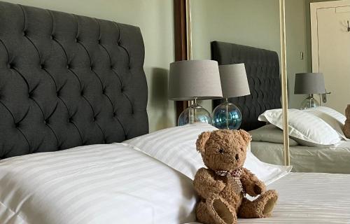 a teddy bear sitting on top of a bed at Cambridge Villa in Warwick
