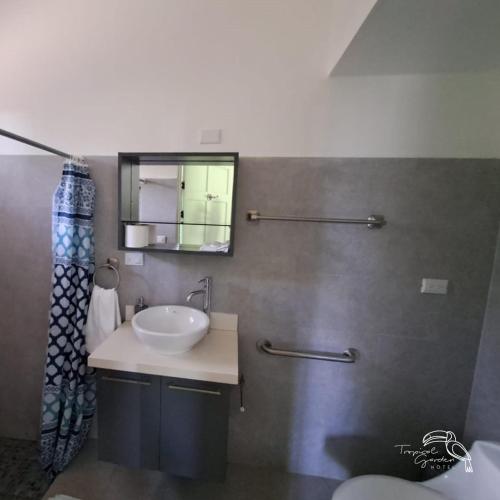 a bathroom with a sink and a mirror at Tropical Garden Hotel in Jacó