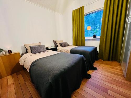 2 Betten in einem Zimmer mit grünen Vorhängen und einem Fenster in der Unterkunft Guestly Homes - 3BR Luxury Beachfront Villa in Piteå