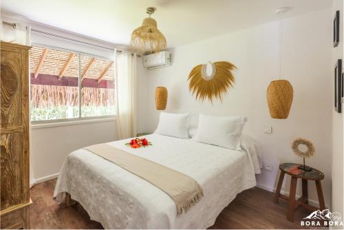 a bedroom with a white bed with flowers on it at Villa Noa Noa - Matira in Bora Bora