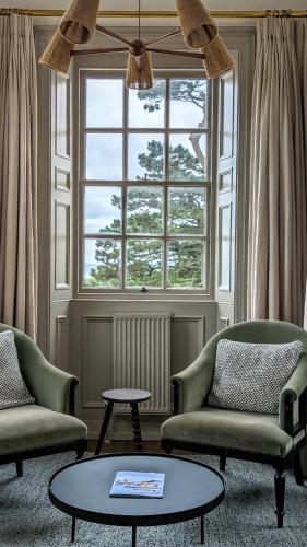 a living room with two chairs and a table and a window at Fowey Hall Hotel in Fowey
