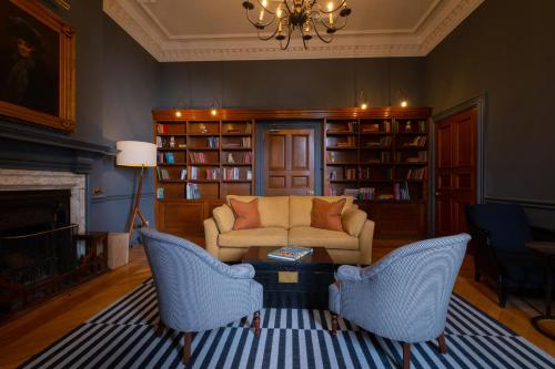 sala de estar con sofá, sillas y chimenea en Fowey Hall Hotel en Fowey