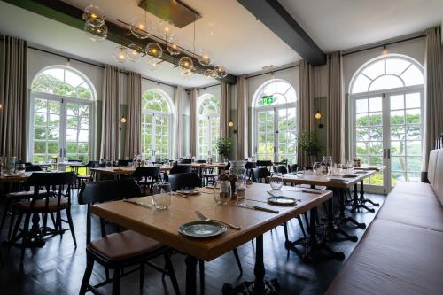 a dining room with tables and chairs and windows at Fowey Hall Hotel in Fowey