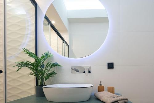 uma casa de banho com uma banheira branca e um espelho redondo em Black Caviar em Asprouliánoi