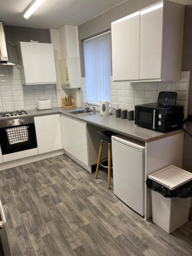 a kitchen with white cabinets and a black microwave at Sheffield spa view 2 bed house free parking in Sheffield