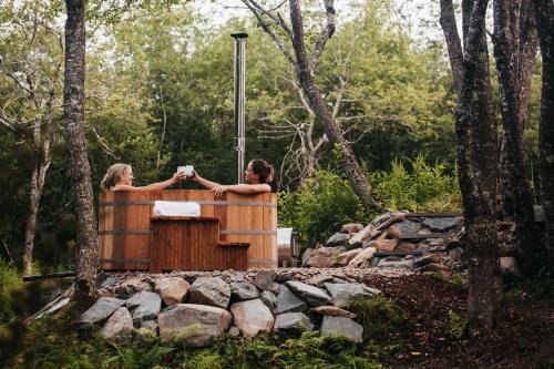 two women standing in a hot tub in the woods at FlowEdge Riverside Getaway in Meaghers Grant