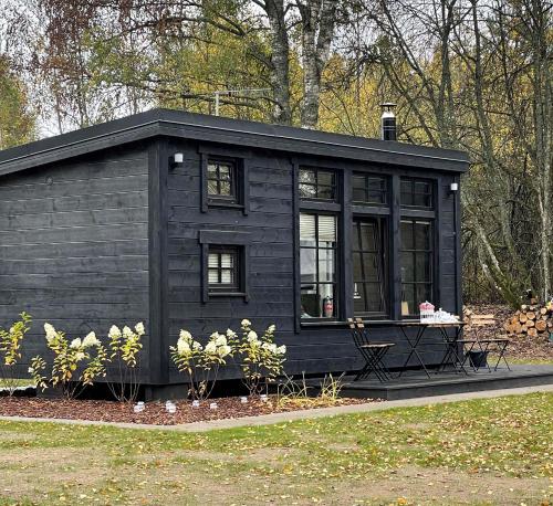 a black tiny house sitting in a yard at Ieviņi atpūtas vieta in Bānūži