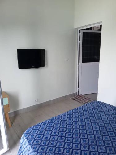a bedroom with a bed and a flat screen tv at Résidence Marie France MENDY in Toubab Dialaw