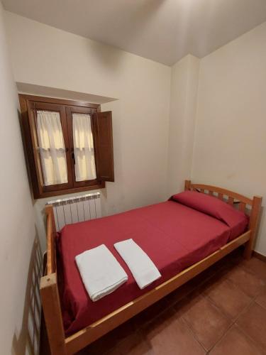 a bedroom with a bed with red sheets and a window at ALBERGUE CASA LAS ANGELITAS in Quel