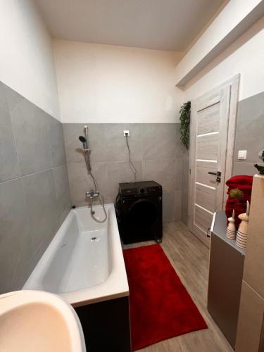 a bathroom with a white tub and a red rug at Apártmany v centre - vlastná izba so spoločnou kuchyňou a kúpeľnou môže byť zdieľaná 2 inými izbami in Martin