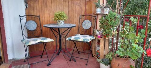 a patio with three chairs and a table and a fence at Hostal Destino Bellavista in Valparaíso