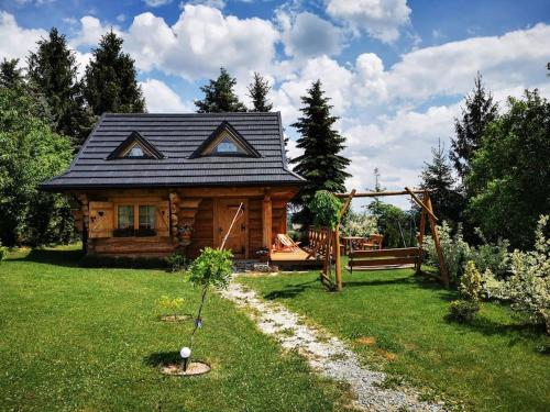 una cabaña de madera en un patio con una valla en Uroczy domek w Rabce-Zdrój, en Zaryte