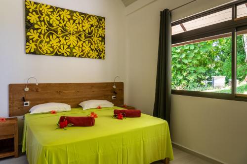 a bedroom with a green bed with red pillows on it at FARE ATEA in Bora Bora