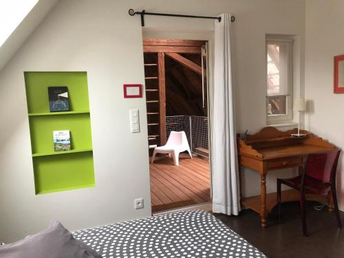 a bedroom with a desk and a door leading into a room at B&B Le Lodge in Bourgheim