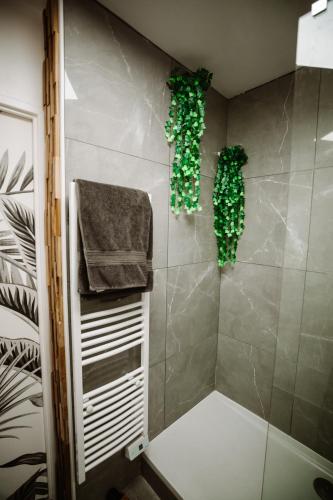 La salle de bains est pourvue d'une douche avec des plantes vertes sur le mur. dans l'établissement L'Échappée Parisienne - Canal St-Denis, à Aubervilliers