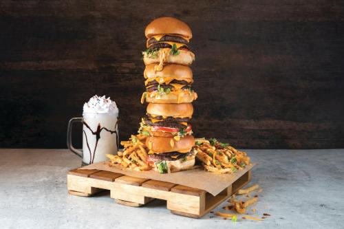 a tall sandwich on a wooden stand next to a drink at Luxor in Las Vegas