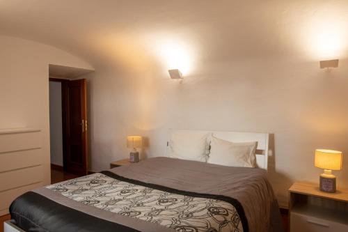 a bedroom with a bed with two lights on the wall at Casas da Avó Alsira in Évora