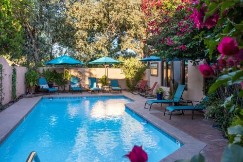 uma piscina com cadeiras e guarda-sóis em Adobe Rose Inn em Tucson