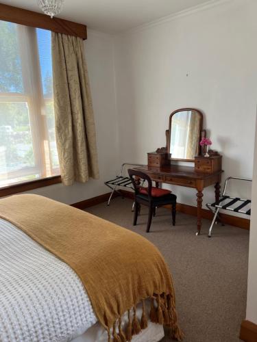 Schlafzimmer mit einem Bett, einem Spiegel und einem Schreibtisch in der Unterkunft The Old Vicarage in Reefton