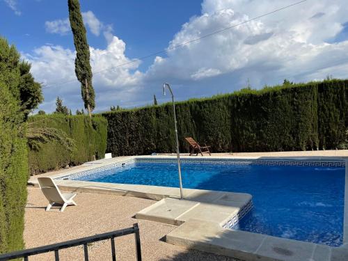 una piscina con una silla junto a un seto en Granada Sights, en Las Gabias