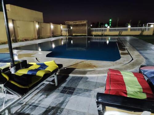 a swimming pool at night with two lounge chairs in front at شاليه بالريف الاوربي للاجازات in Giza