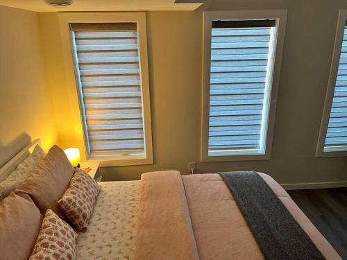 a bedroom with a bed and two windows with shutters at Cozy Private 1 bedroom basement suite - free parking and free Wifi in Winnipeg