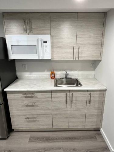 a kitchen with a sink and a microwave at Cozy Private 1 bedroom basement suite - free parking and free Wifi in Winnipeg