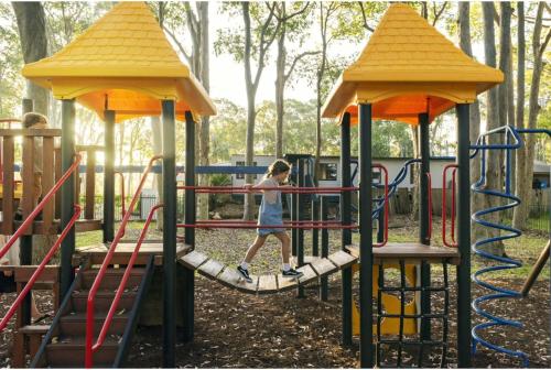 ein kleines Kind auf einer Rutsche auf einem Spielplatz in der Unterkunft Discovery Parks - Narooma Beach in Narooma