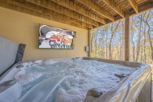 een hot tub in een kamer met een groot raam bij Large Luxury House, 4 King Beds & 21 Total, Hot Tub, Theater, Fireplace, Game Room, Ping-pong, Pool Table, Air Hockey, Arcade, River, Big Kitchen, Nice Porch, Quiet, Good for Families and Large Groups, Near UGA Golf Course, Close to UGA & Stanford Stadium in Athens