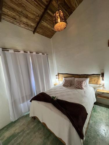 a bedroom with a large bed with white curtains and a chandelier at La Casita de Charo 2 in Constanza