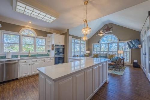 a large kitchen with white cabinets and a large island at Large Luxury House, King Beds and More, Hot Tub, Theater, Fireplace, Game Room, Ping-pong, Pool Table, Air Hockey, Arcade, River, Big Kitchen, Nice Porch, Quiet, Good for Families and Large Groups, Near UGA Golf Course, Close to UGA & Stanford Stadium in Athens