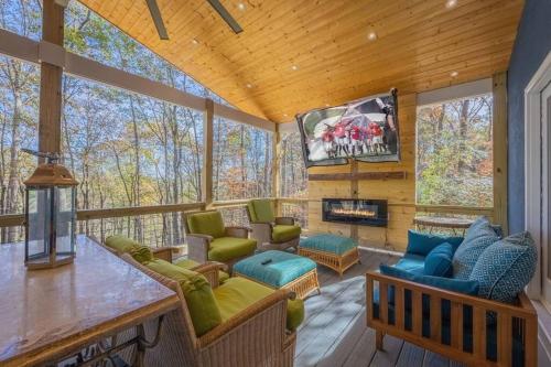 a screened in porch with a living room with a tv at Large Luxury House, King Beds and More, Hot Tub, Theater, Fireplace, Game Room, Ping-pong, Pool Table, Air Hockey, Arcade, River, Big Kitchen, Nice Porch, Quiet, Good for Families and Large Groups, Near UGA Golf Course, Close to UGA & Stanford Stadium in Athens