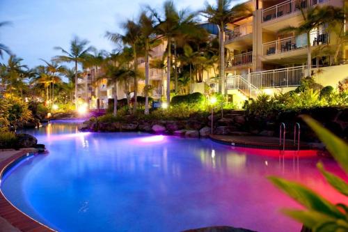 a swimming pool in front of a hotel at night at Resort Queen Studio at Alex Beach Resort in Alexandra Headland