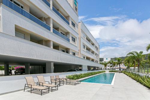 um pátio do hotel com cadeiras e uma piscina em Cannes Club Residence a 200m da praia, recém inaugurado em Florianópolis