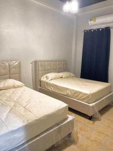 two beds in a room with blue curtains at Centrico Apartamento Barrio de La Exposición in Panama City