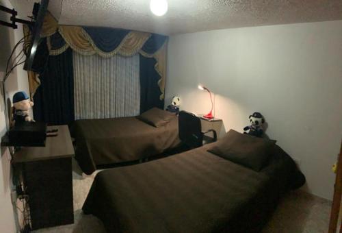1 dormitorio con 2 camas, escritorio y lámpara en cómoda habitación cerca al aeropuerto, en Bogotá