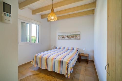 a bedroom with a bed with a striped blanket at Villa Mercedes in Cala Morell