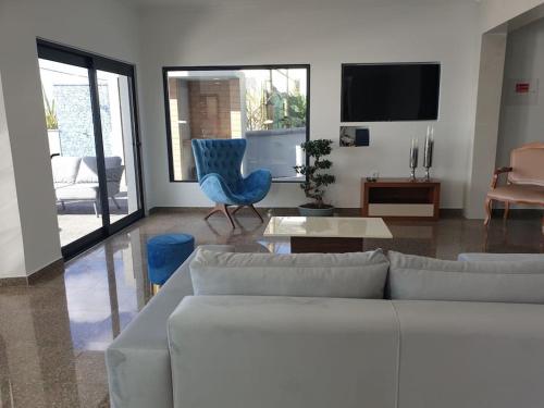 ein Wohnzimmer mit einer weißen Couch und einem blauen Stuhl in der Unterkunft Villa Sunset Avenue in Paul do Mar