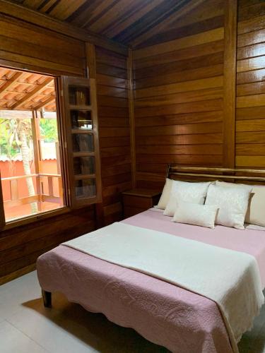 Un dormitorio con una cama con paredes de madera y una ventana en Pousada Chateau Pireneus, en Pirenópolis