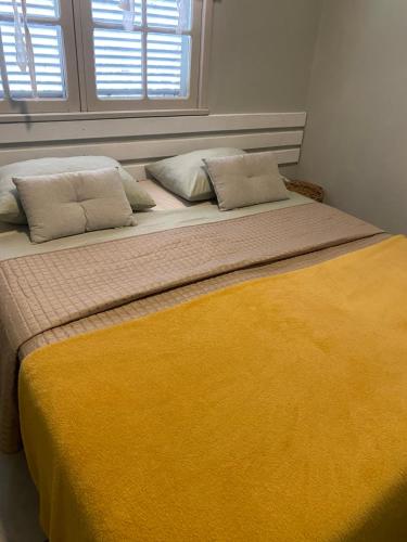 a bed with two pillows and a yellow blanket at Solar 197 Pousada in Timbó