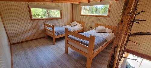 a small room with two beds and two windows at Ciprés del Conguillio in Melipeuco