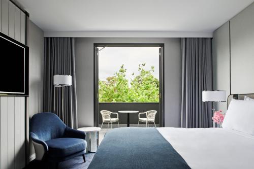1 dormitorio con 1 cama, 1 silla y 1 ventana en The Royce, en Melbourne