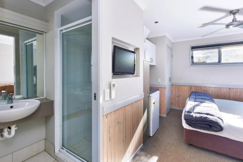 a bathroom with a sink and a toilet and a tub at NRMA Sydney Lakeside Holiday Park in Narrabeen